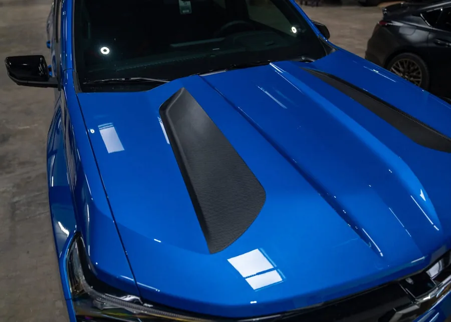 Close-up of gloss blue wrap and carbon fiber hood detailing